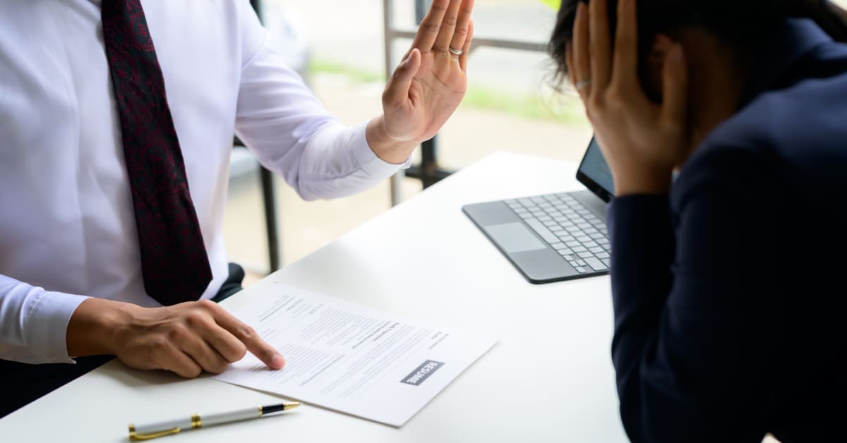 image of a man in tie pointing to a paper and holding his finger up in denial