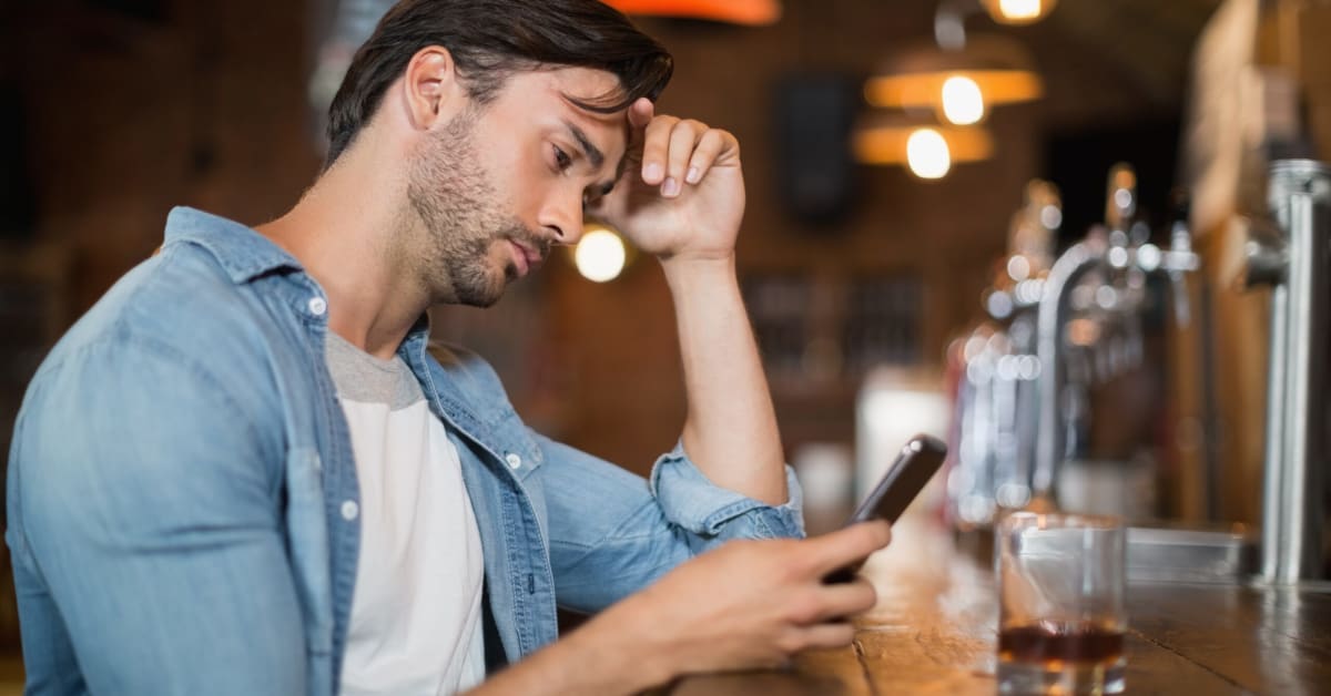 image of a young man looking down at his mobile phone