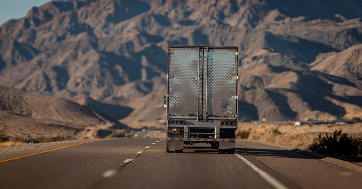 image of the rear of a truck traveling on a road through mountainous desert image of the rear of a truck traveling on a road through mountainous desert