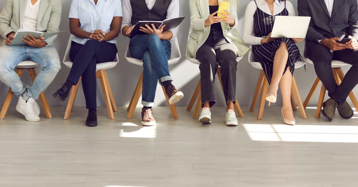 several people waiting in line in chairs on laptops