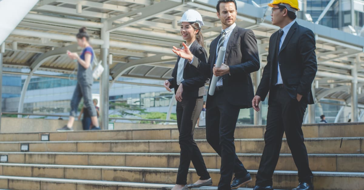 image of people in suits and hardhats walking down stairs outside a building