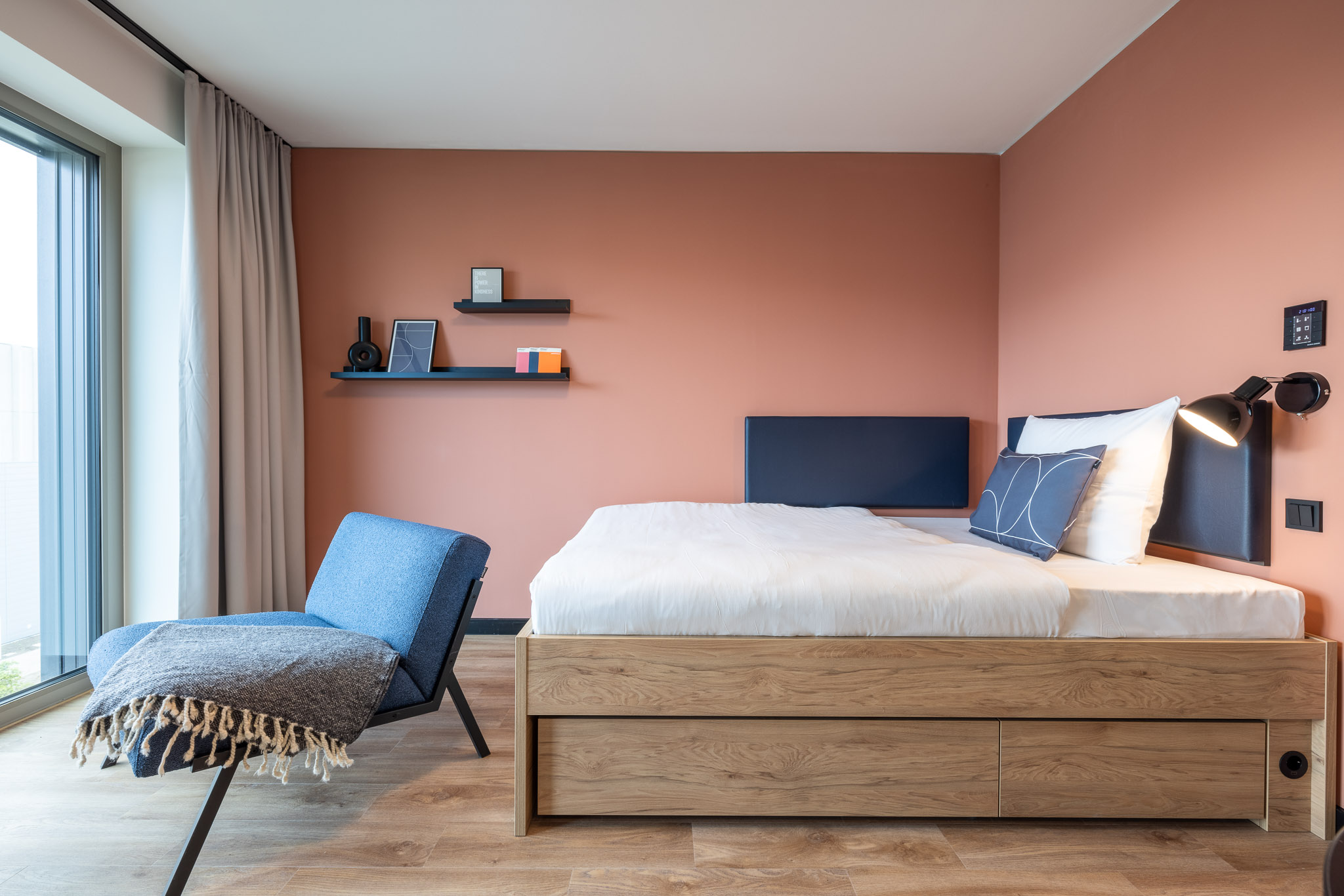 The Base Grand Apartment – view of the bed, shelf and armchair