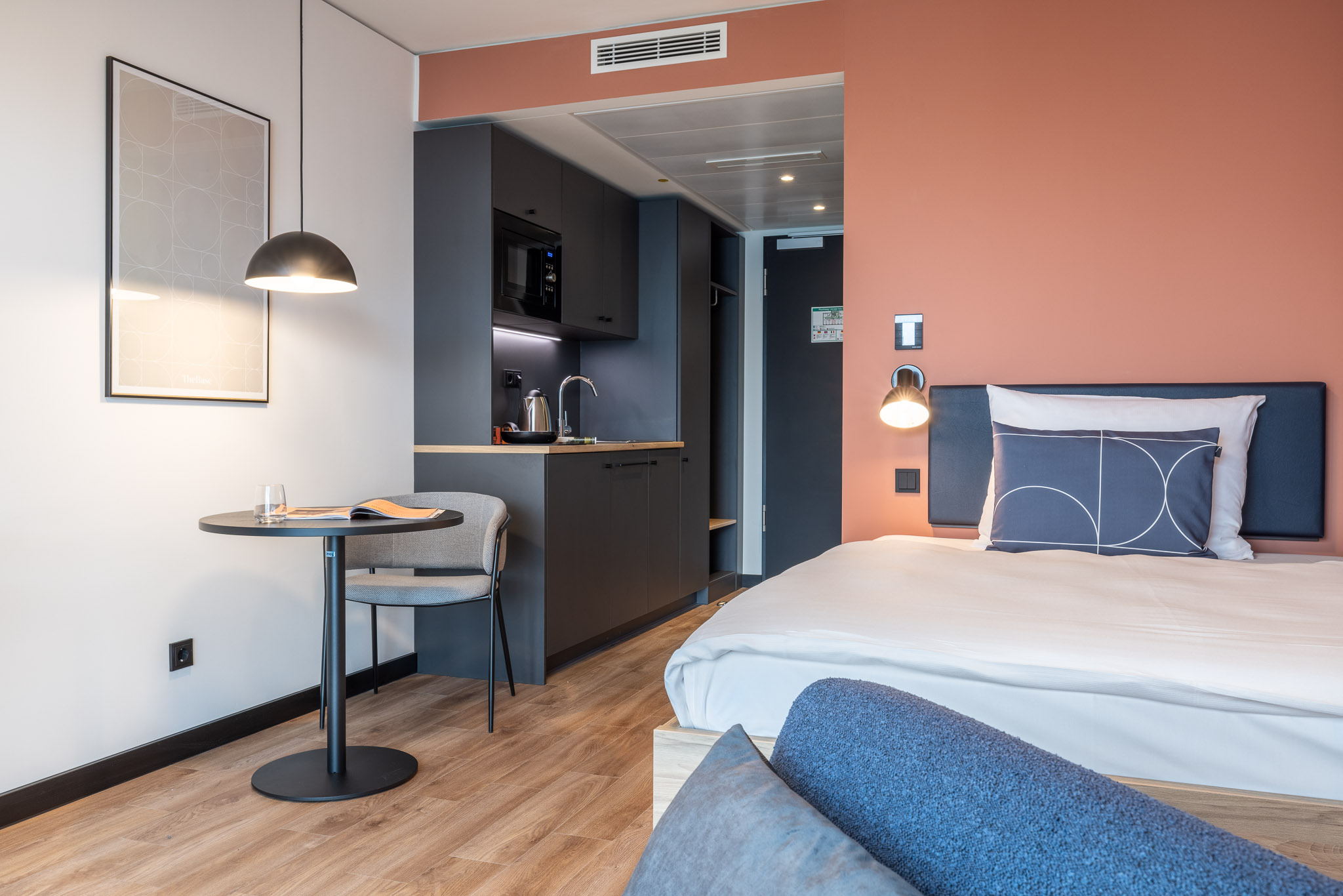 Modern apartment at The Base Munich with bed, kitchenette and seating area