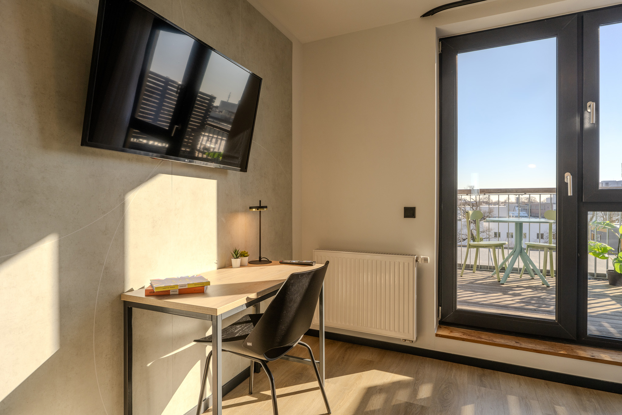 Schreibtisch, Terrasse und Fernseher sind Teil der Coliving Wohnung in Berlin