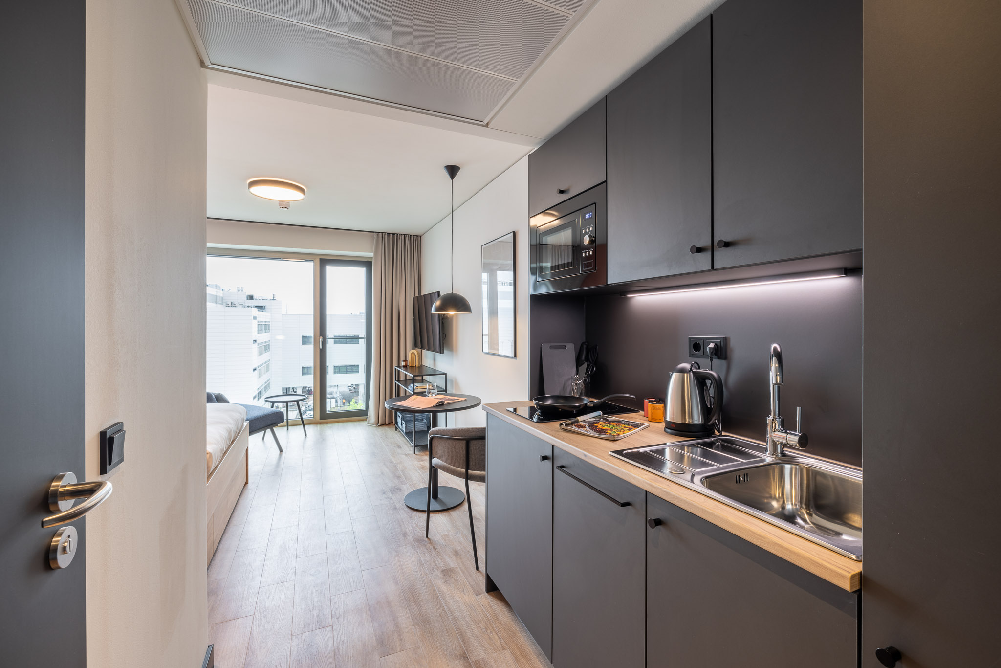 The Base City View Apartment at The Base Munich – bed, kitchenette and desk setup