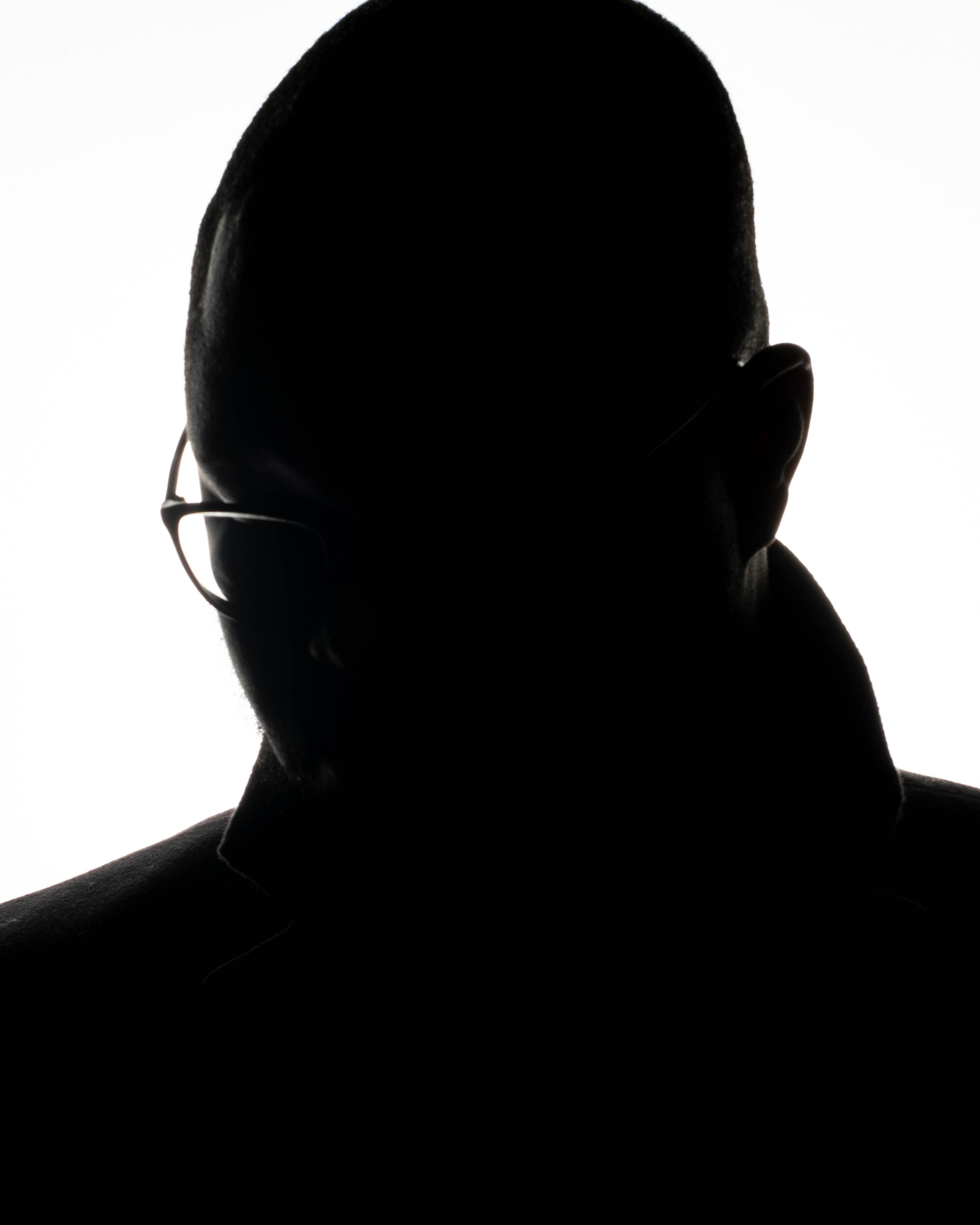 a silhouette of a man wearing glasses looking off to the right