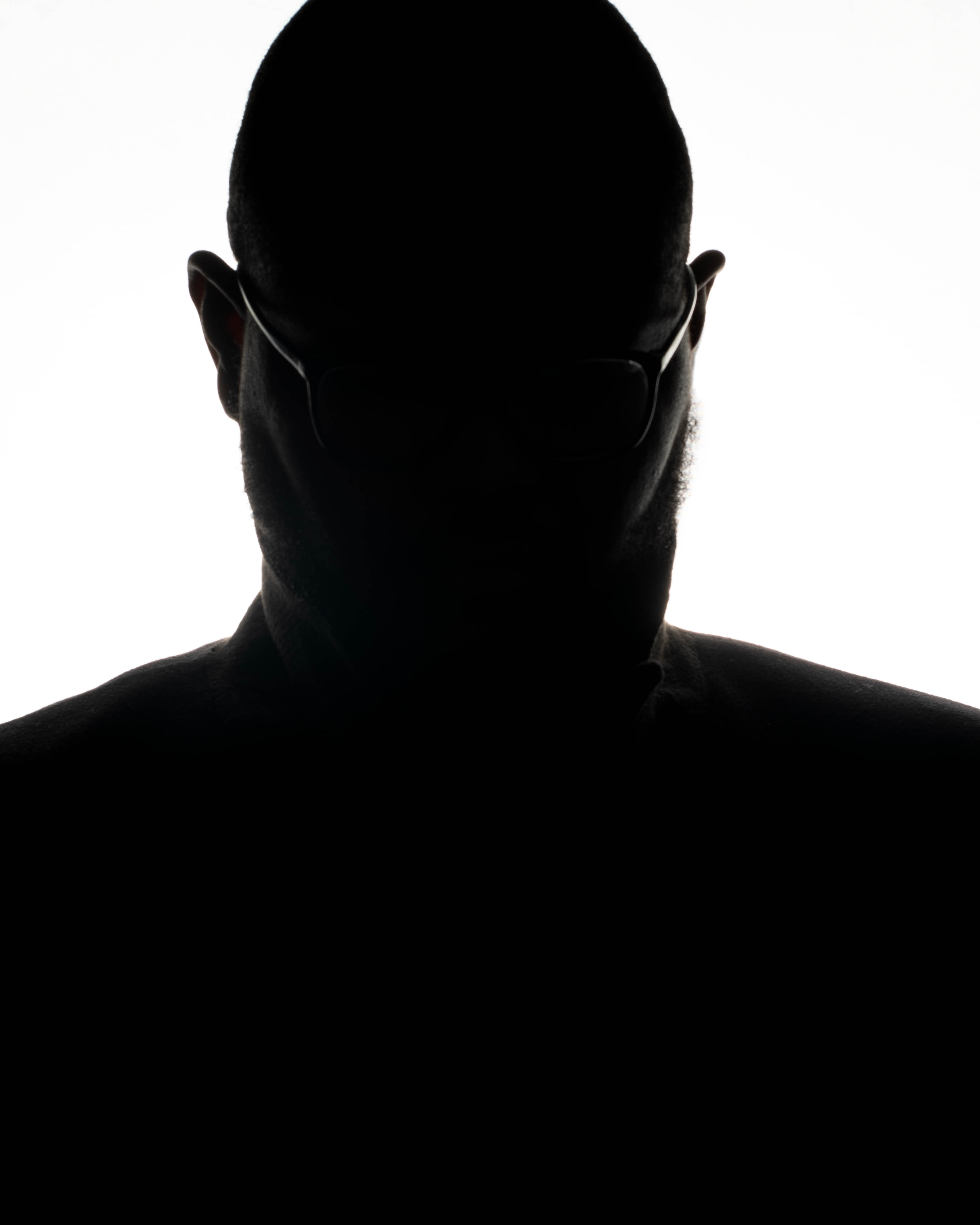 a silhouette of a man wearing glasses looking off to the right