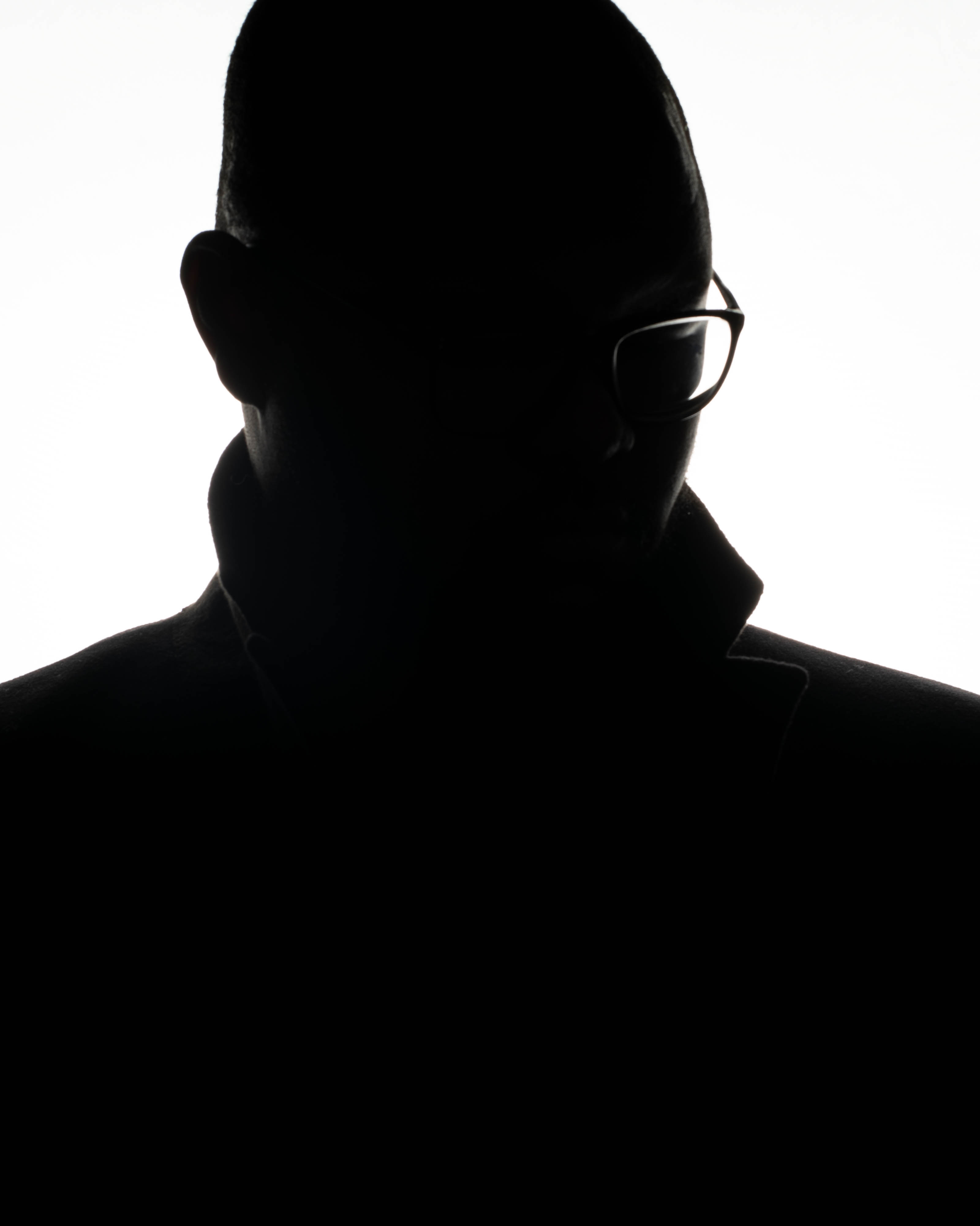 a silhouette of a man wearing glasses looking off to the right