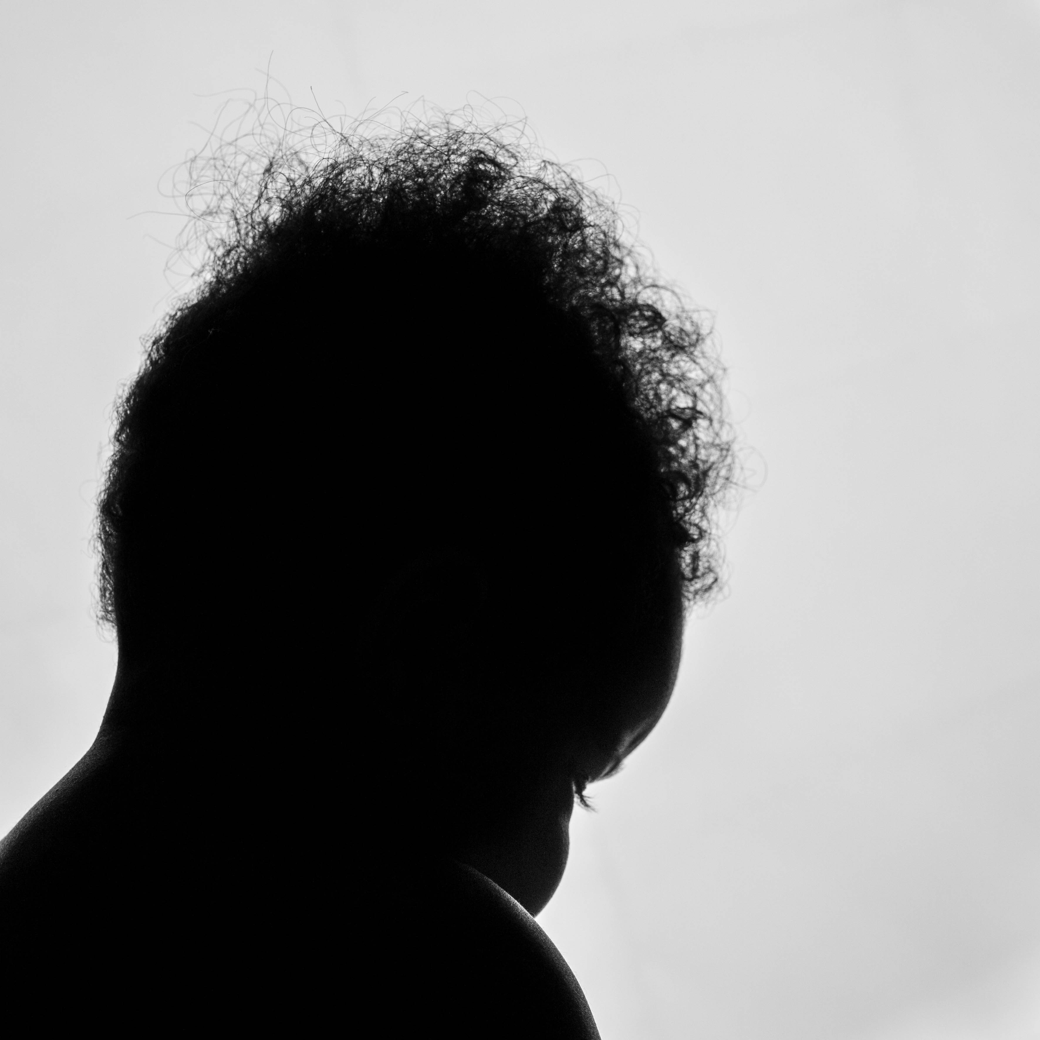 a silhouette of a man wearing glasses looking off to the right