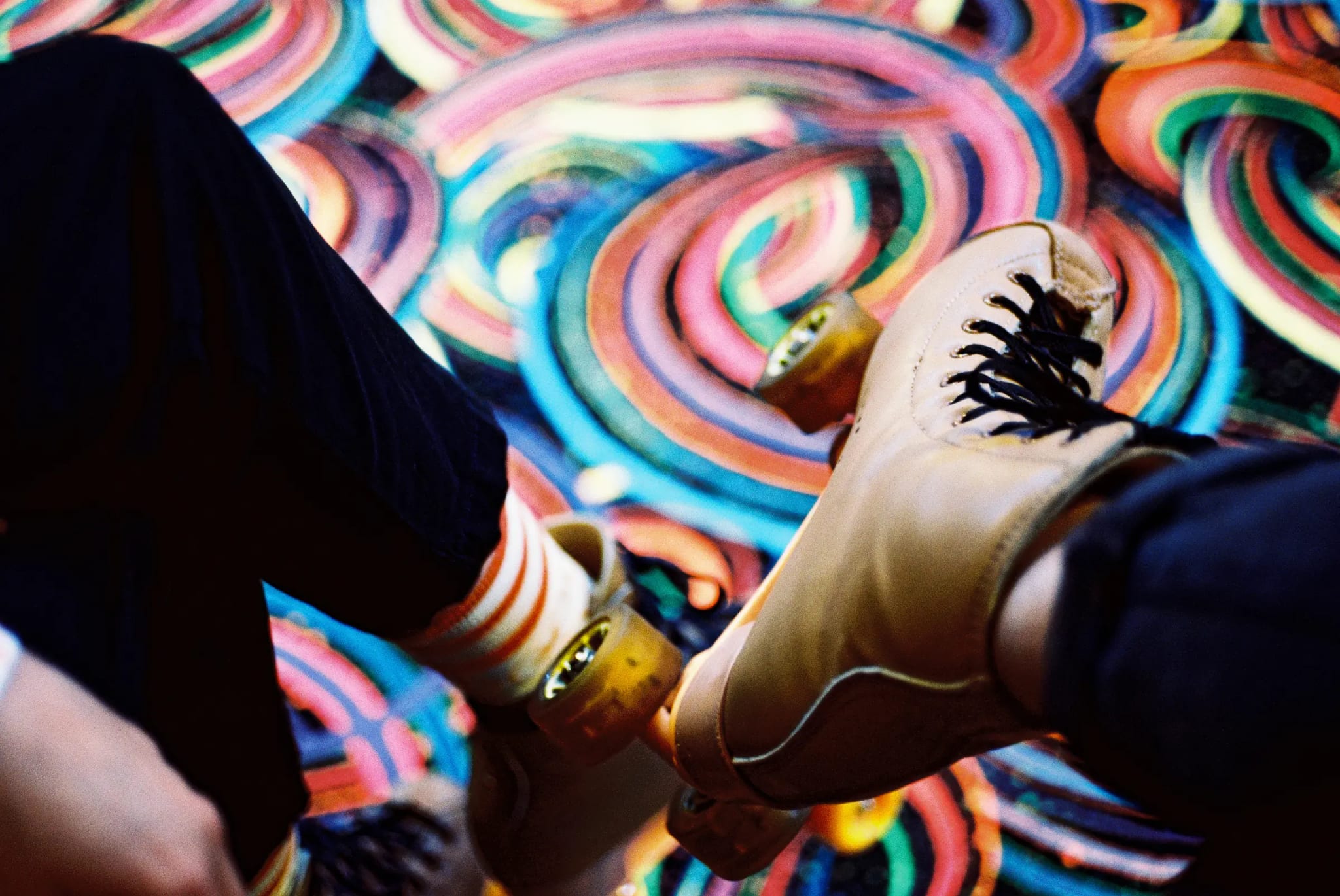 Roller skates glide across a vibrant, swirling disco floor.