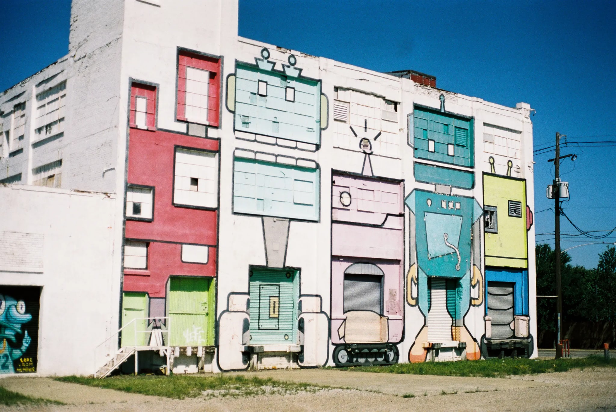 White building facade with colorful robot murals integrating windows and doors into the designs.