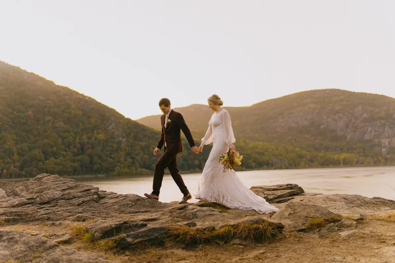 Hudson Valley micro wedding couple walking across rocky cliffs overlooking the Hudson River at Cold Spring