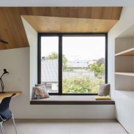 Helles Homeoffice mit Holzschreibtisch, großem Josko Fenster mit Sitzbank und offenen Regalen.