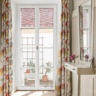 Helle doppelflügelige Terrassentür von Josko mit floralen Vorhängen; draußen stehen Töpfe mit Kakteen auf einem kleinen Balkon.