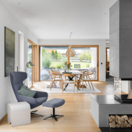 Lichtdurchfluteter Wohn- und Essbereich mit großzügigen Glasfronten, warmen Holzoberflächen und modernem Kamin – ein harmonisches Zusammenspiel aus Design, Komfort und Naturbezug.