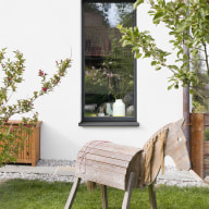 Modernes Holz-Alu-Fenster in klarer, reduzierter Architektur – kombiniert mit natürlicher Umgebung und liebevollen Details im Garten.