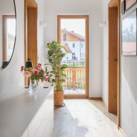 Lichtdurchfluteter Gang mit großzügigem Holzfenster und klarer Linienführung – natürliche Materialien und warmes Licht verbinden modernes Design mit Wohnlichkeit.