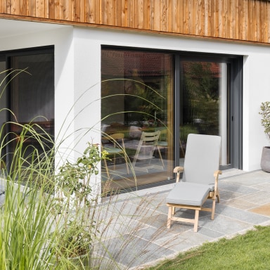 Großzügige Glas-Schiebetüren von Josko verbinden Wohnraum und Terrasse harmonisch – für fließende Übergänge zwischen Innen und Außen und lichtdurchflutetes Wohnen.