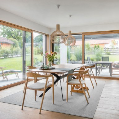 Offener Essbereich mit großzügigen Glasfronten von Josko, die Innenraum und Garten nahtlos verbinden – natürliche Materialien, viel Licht und ein Gefühl von Weite.