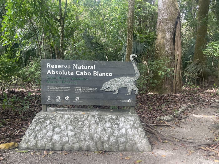 The stone entrance sign for the Cabo Blanco Absolute Nature Reserve, surrounded by forest