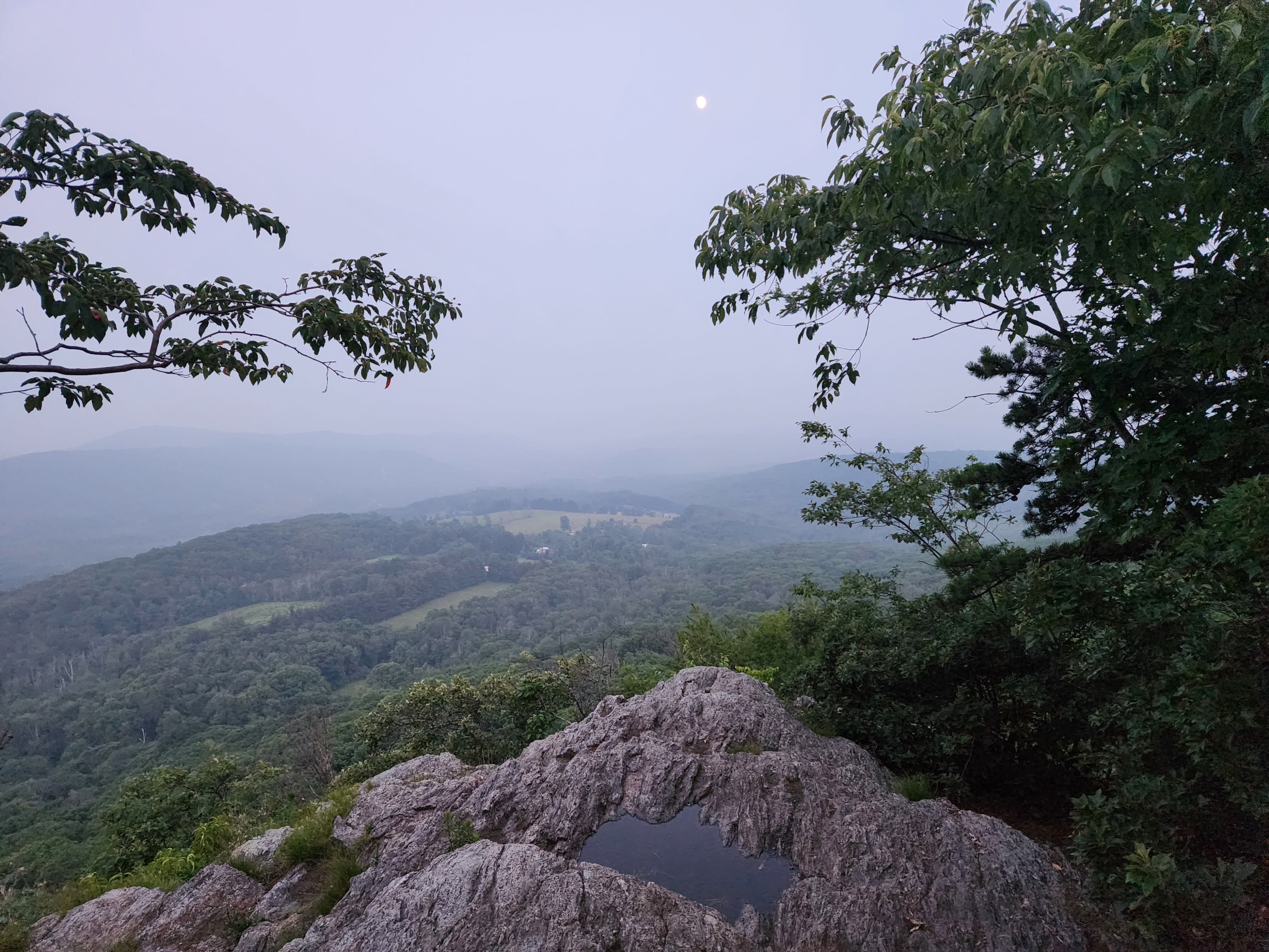 The moon over a foggy view and rocky cliffs