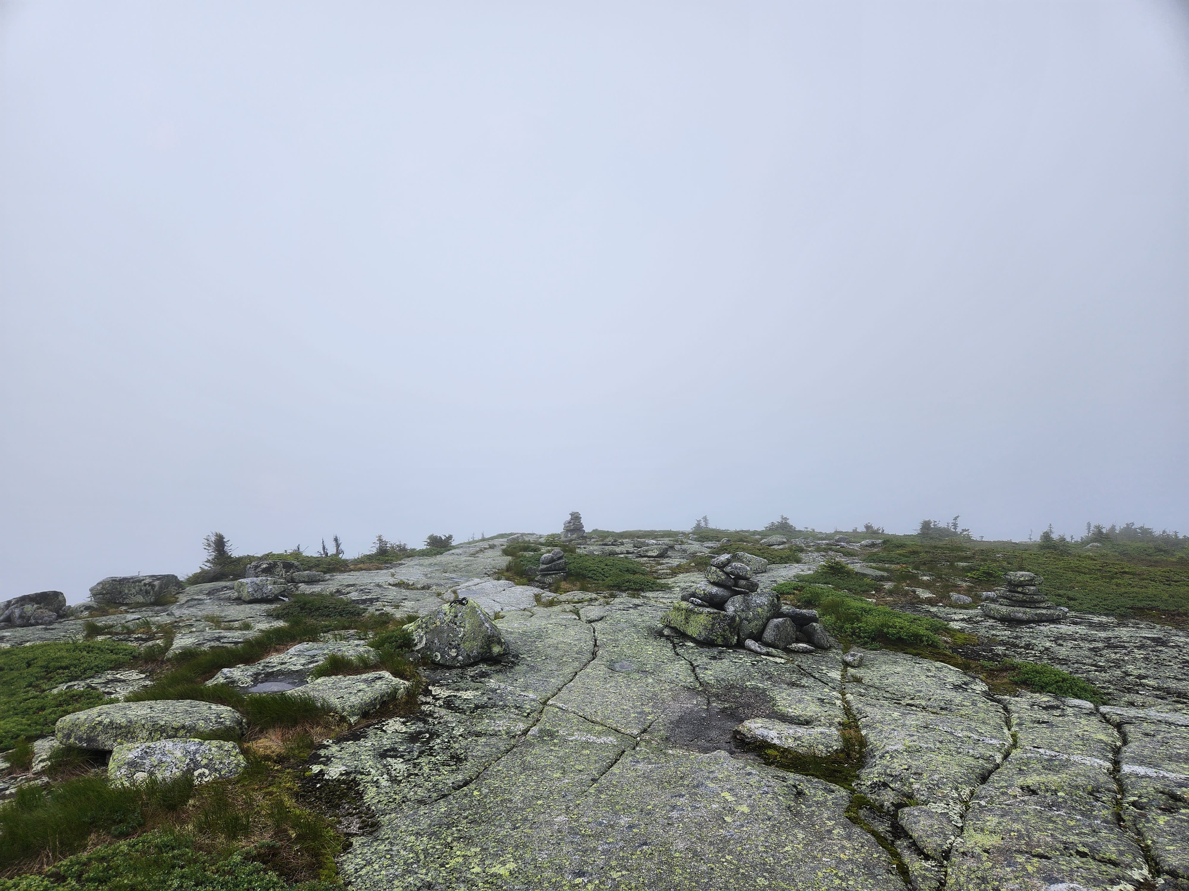 Alpine ridge trail followng rocky cairns into the fog