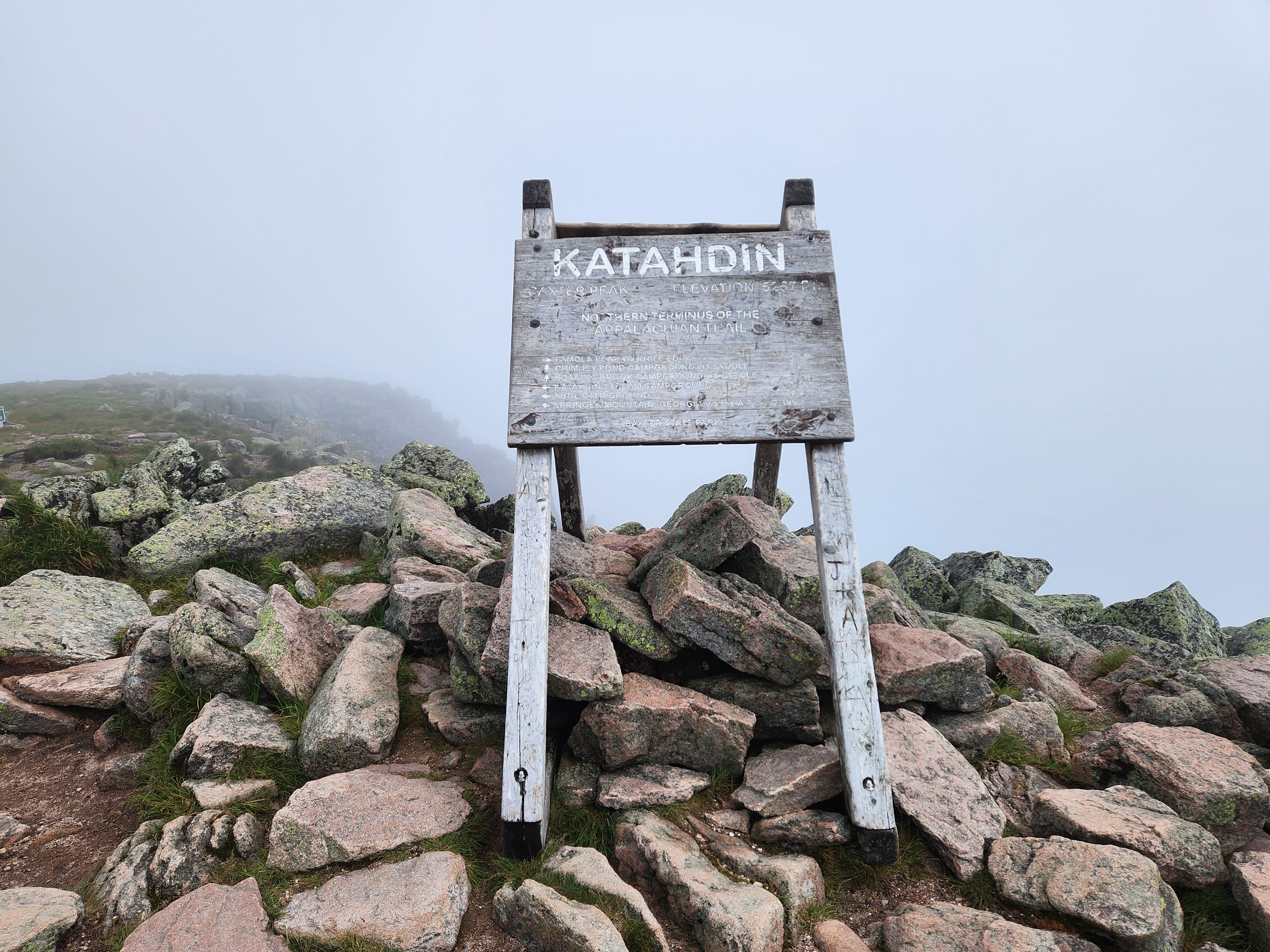 Trail sign on top of Mount Katahdin surrounded by fog