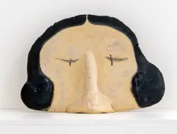 stoneware sculpture of a head with black hair and closed eyes