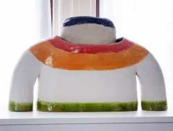 stoneware sculpture of a head wearing a shire with red, orange and green stripes