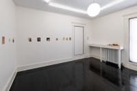 gallery installation four drawings above a fireplace and two paintings on opposite walls