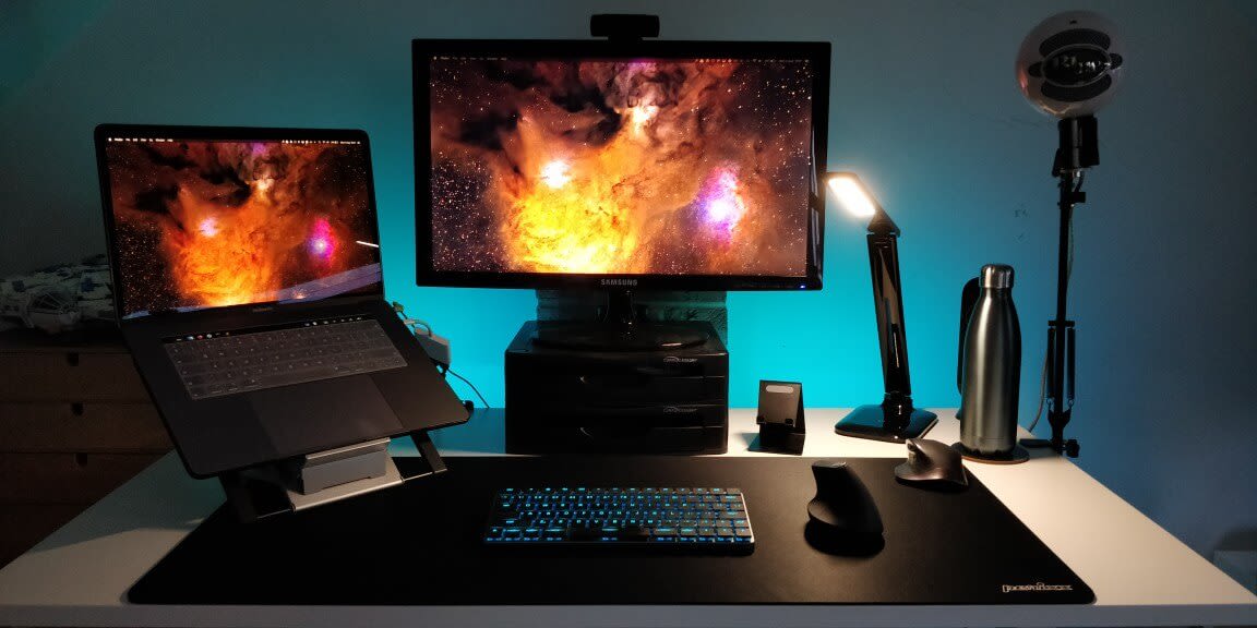 Photo of my home office desk showing my monitor, macbook pro, desk lamp, keyboard and two computer mice.