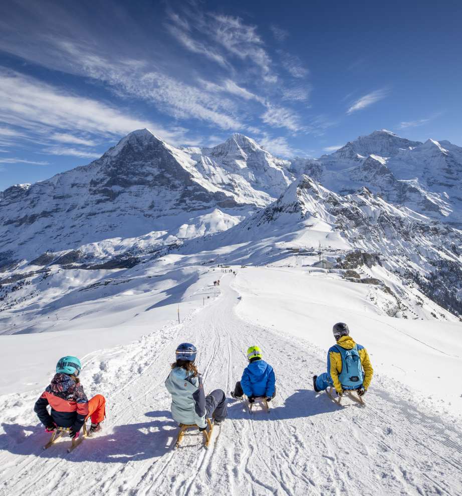 Maennlichen Familie Schlitteln nebeneinander Eiger Moench Jungfrau