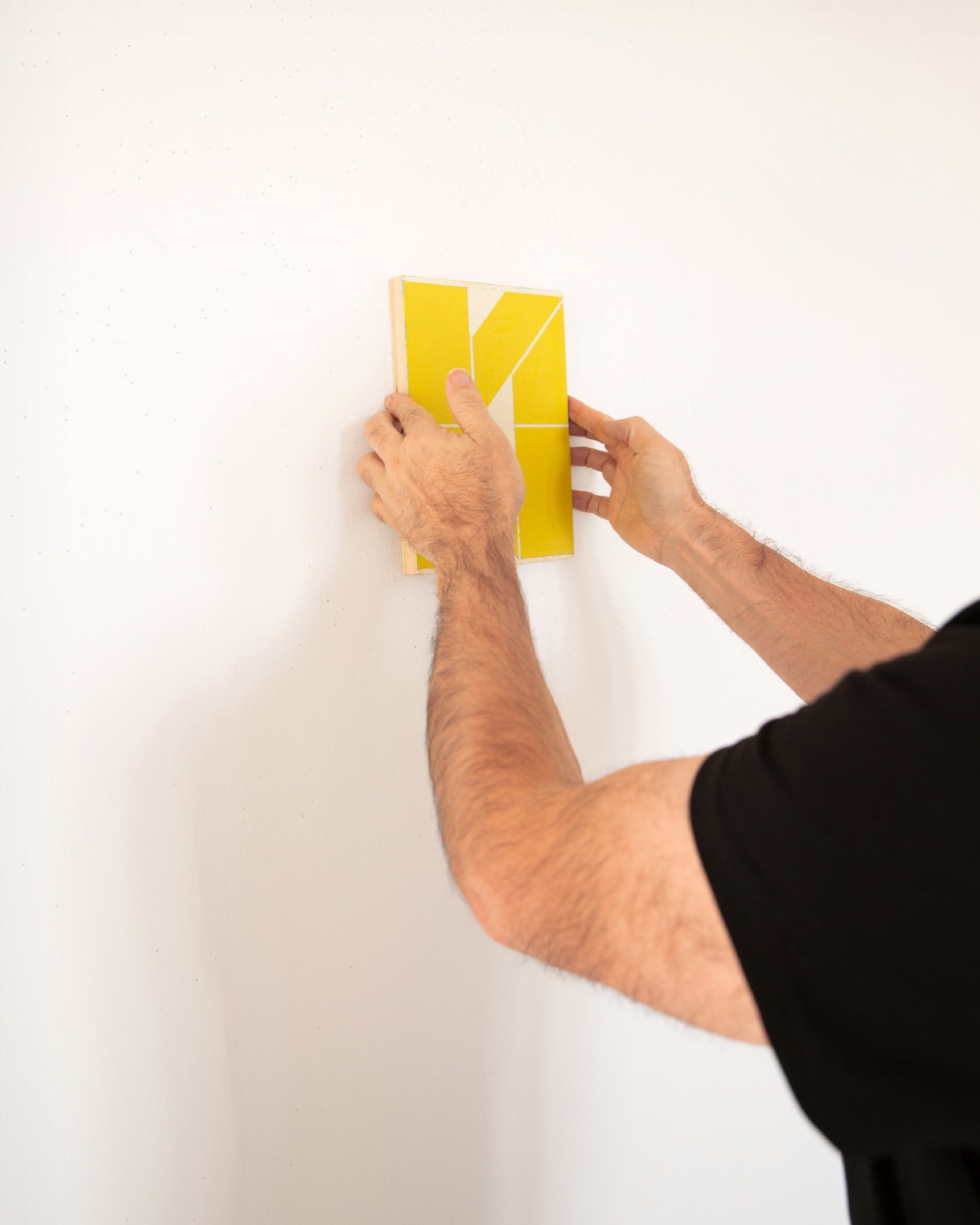 Gelber Stoffsample wird an eine weiße Wand gehangen