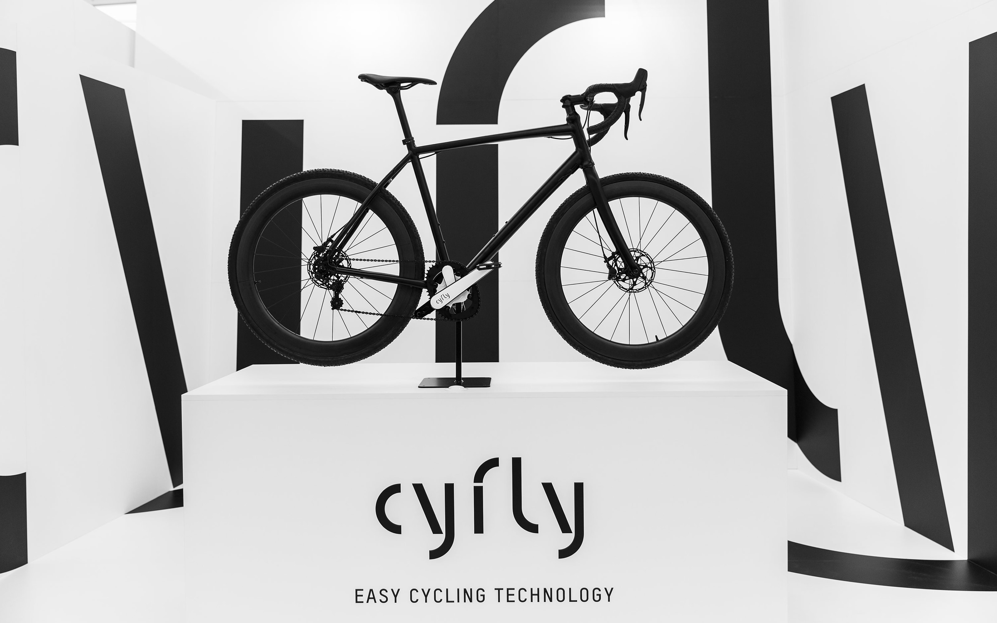 Messestand mit einem Fahrrad auf einem weißen Block mit cyfly-Logo