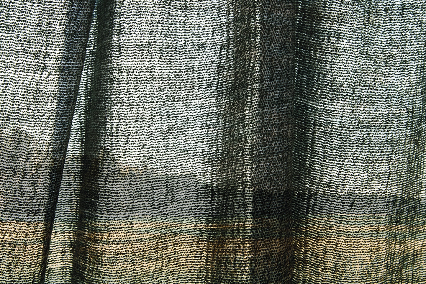 Key visual: Green curtain. In the background a landscape shines through the fabric.