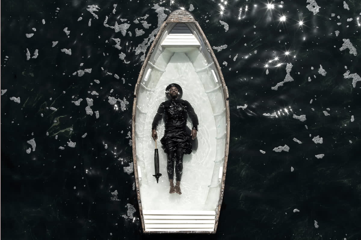 Rowing boat filled with water with woman lying in the middle of the ocean