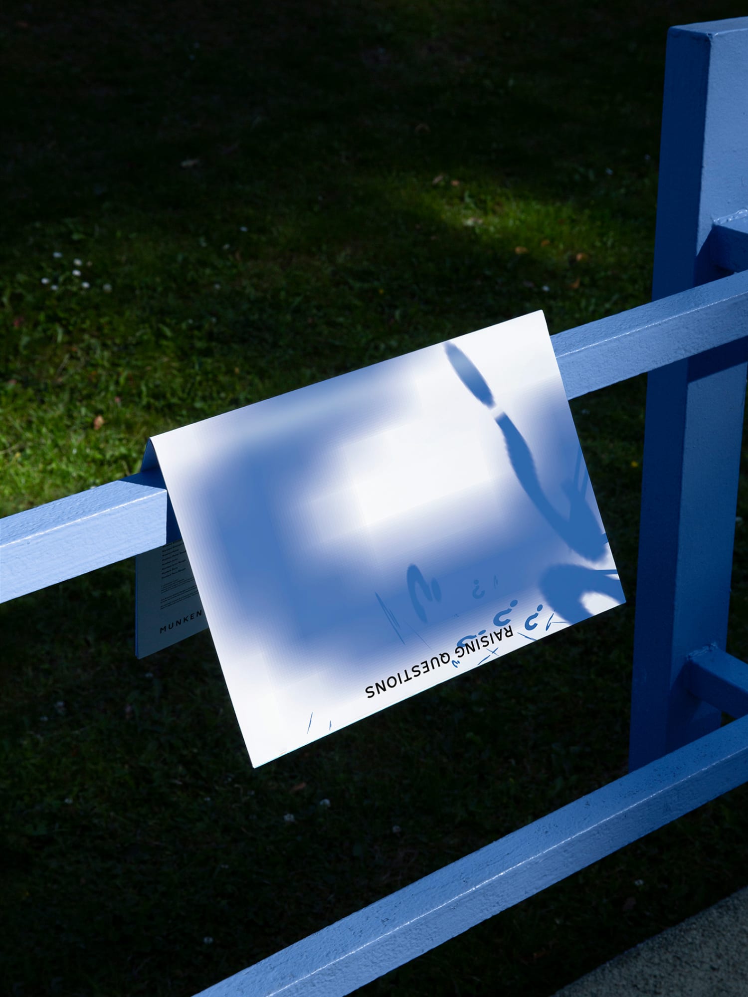 Magazine hanging above a blue steel frame. Green lawn can be seen in the background.