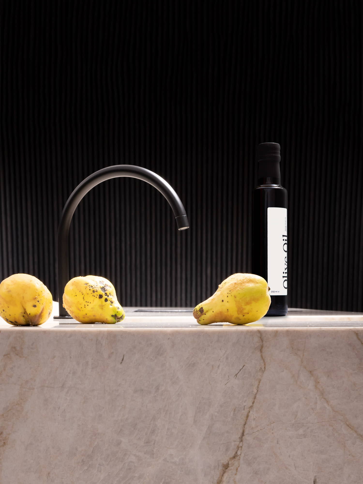 Poggenpohl-Olivenöl auf einer Küchentheke mit Spülbecken und drei Birnen im Vordergrund.