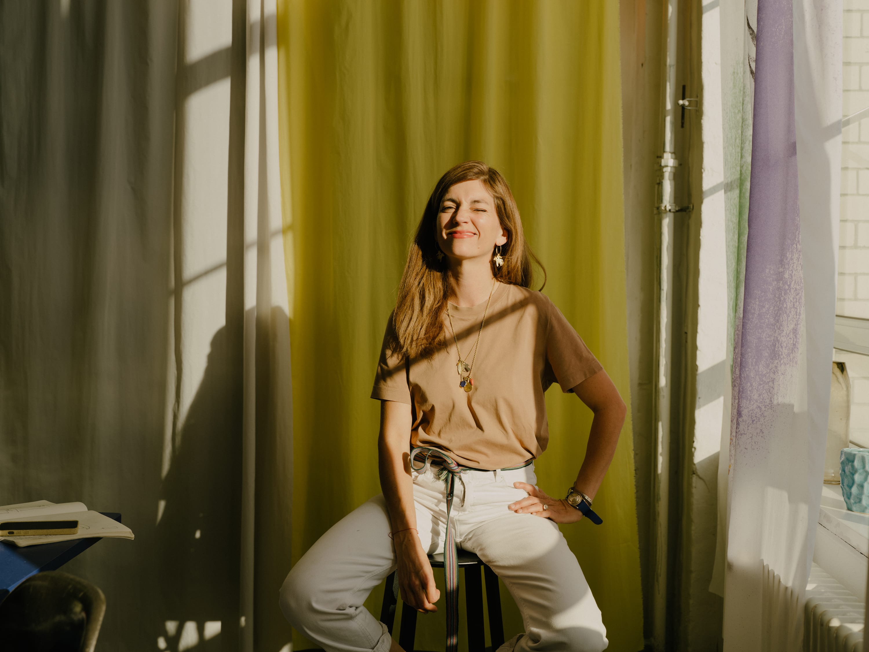 Sarah Illenberger sitting on a stool in the studio.