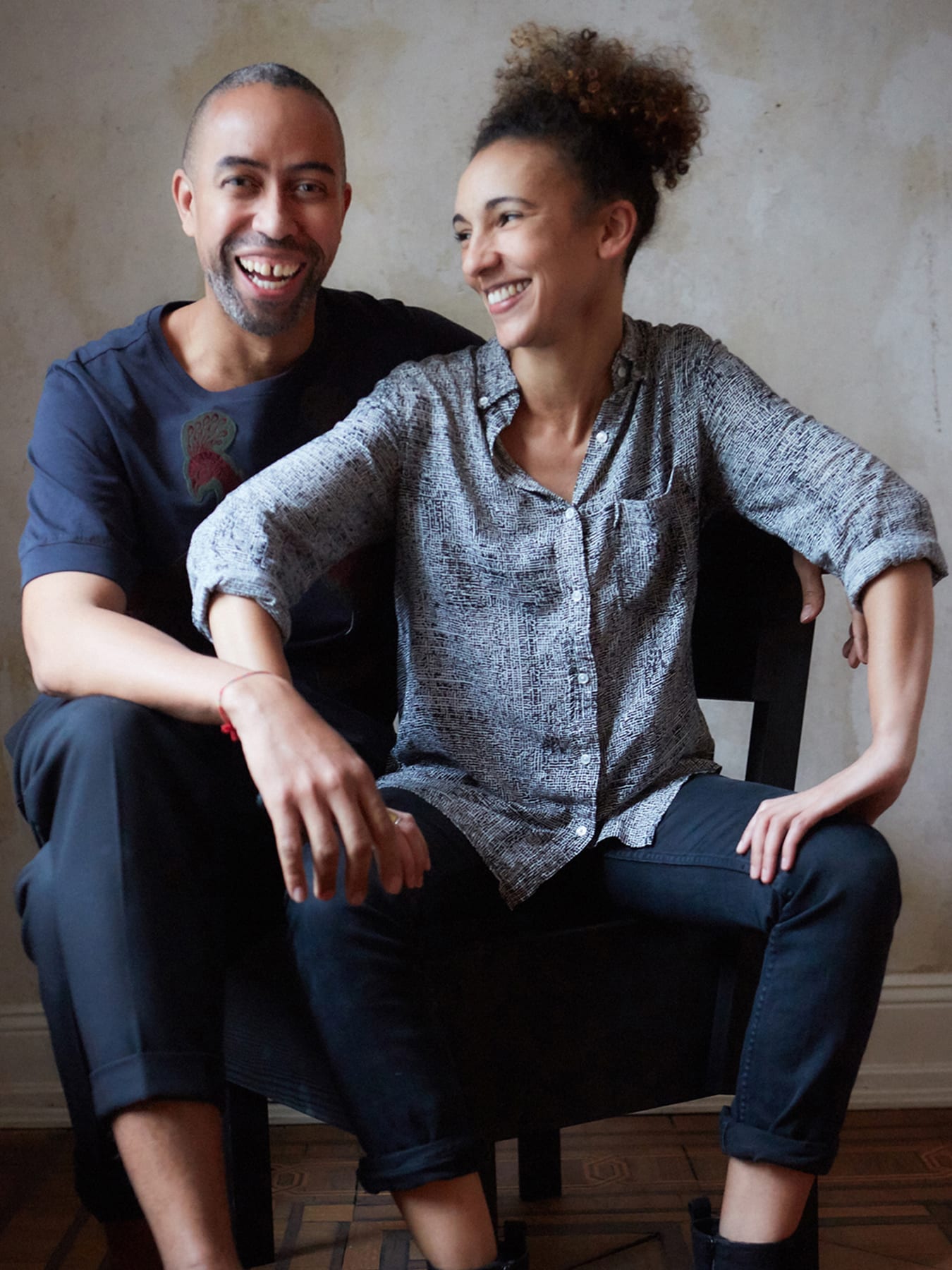 Two laughing people sitting on a chair