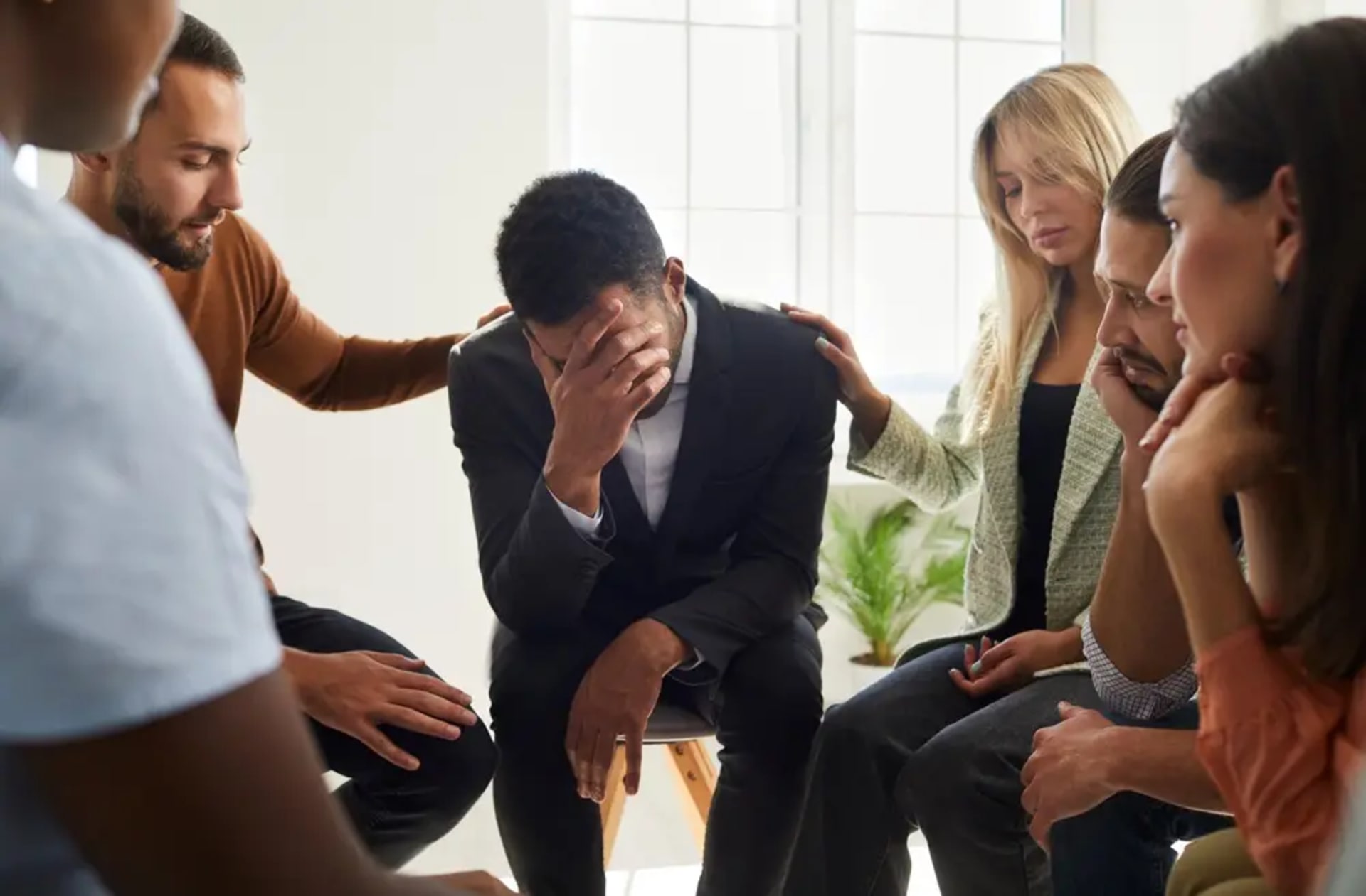 A group of six people sit in a circle during group therapy