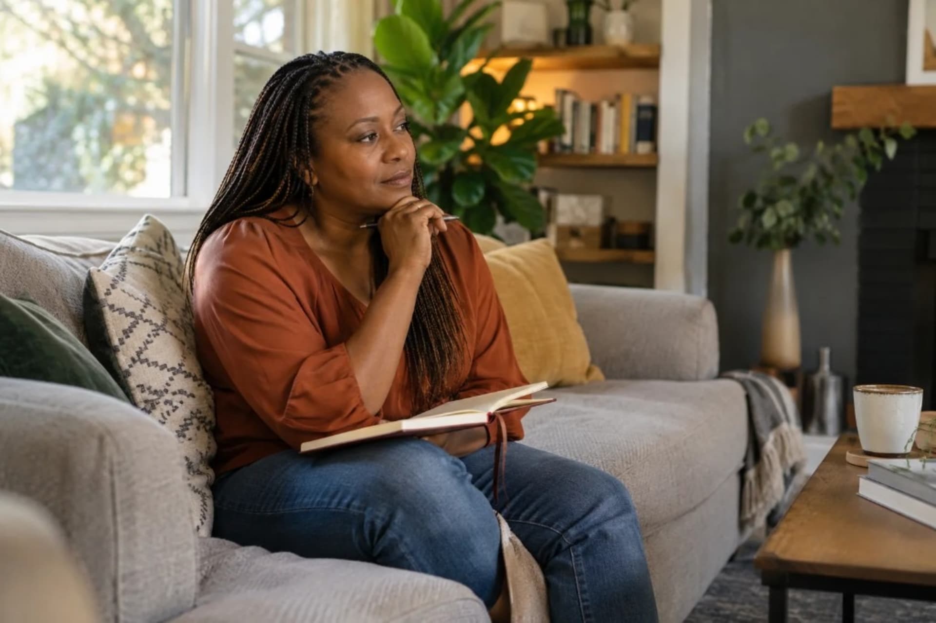 Woman sitting on a sofa with a journal, looking thoughtful during perimenopause depression