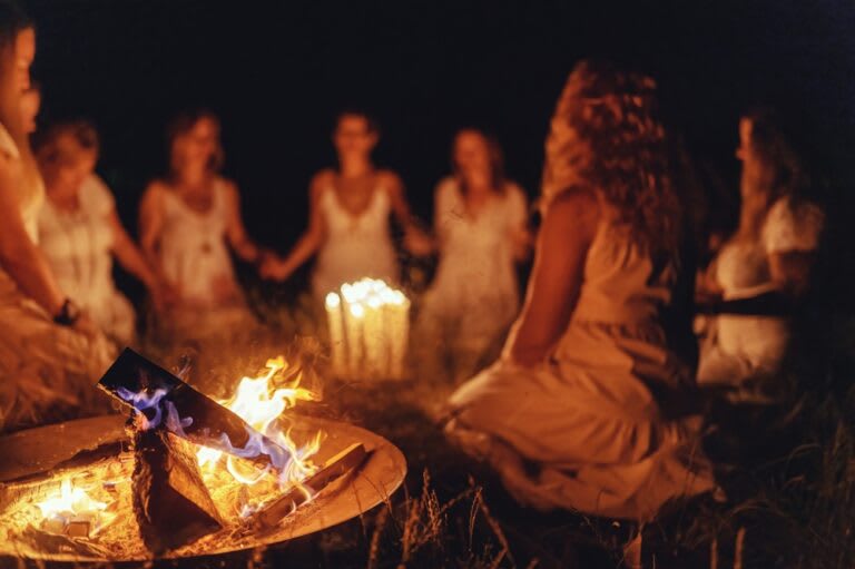 A group of people seated in a circle around a campfire at night