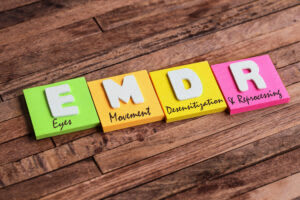 Four colorful sticky notes on a wooden surface spell "EMDR," each labeled: Eyes, Movement, Desensitization, and Reprocessing—a visual representation of EMDR Therapy, a popular trauma treatment also offered by Bay Area CBT specialists.