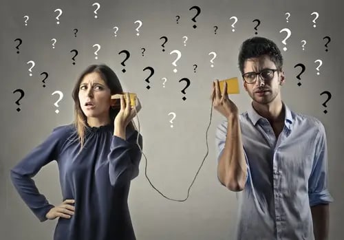 A woman and a man hold tin can telephones with confused expressions. Question marks surround them, suggesting miscommunication or uncertainty. This highlights the need for therapy and counseling in Roseville, California to improve their communication skills.
