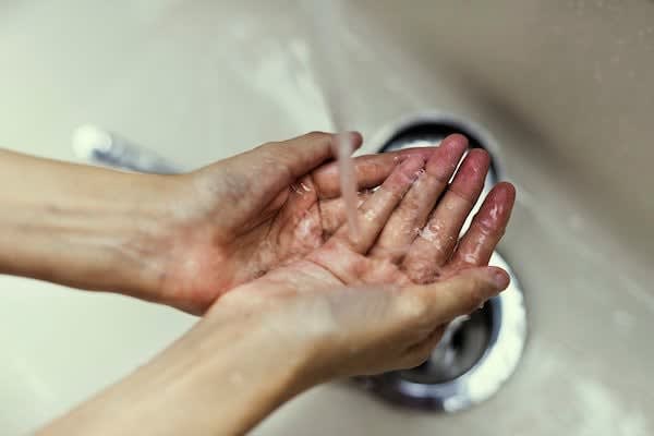 Hands being rinsed under running water at a sink, a simple gesture of self-care encouraged by Roseville therapists to pr