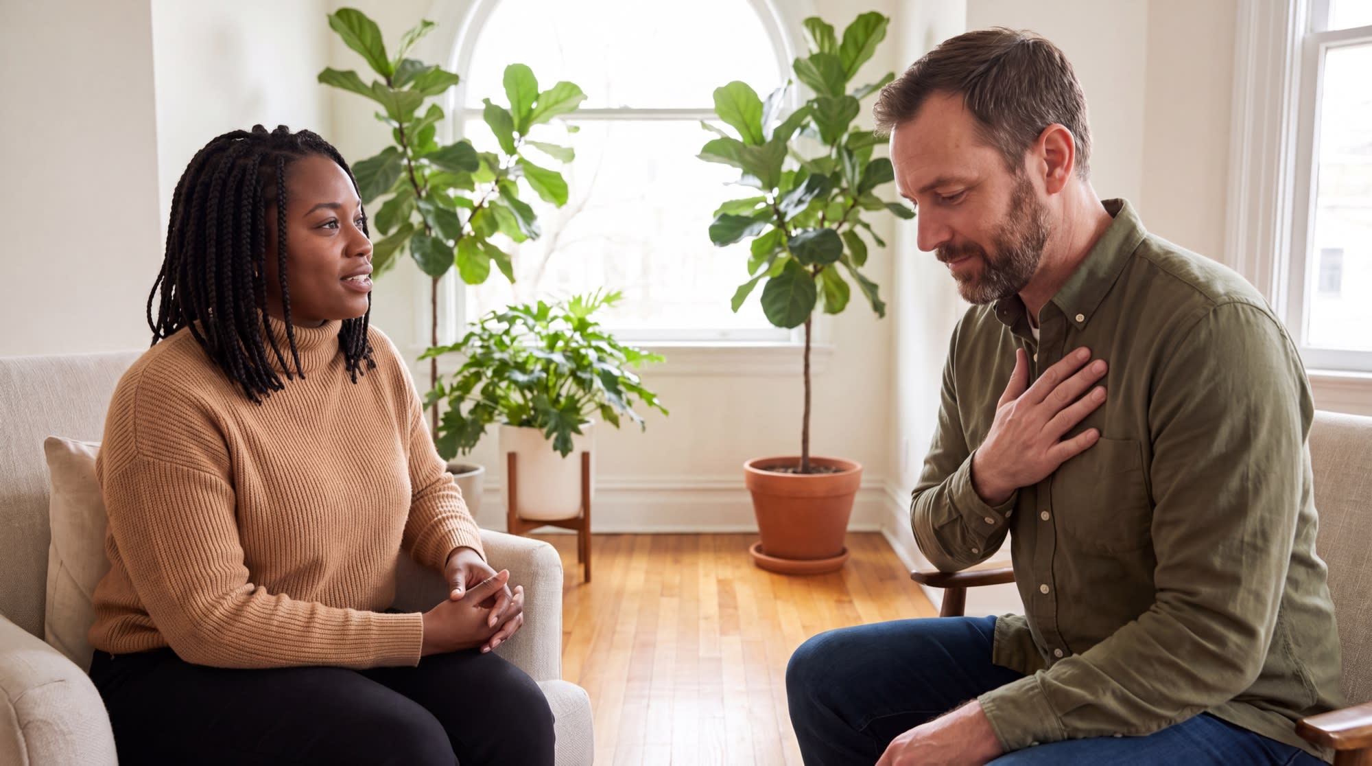 A client resting a hand on his chest to notice a body sensation while his therapist listens attentively.