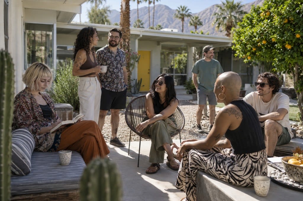 Adults relax with books and coffee in a sunny desert courtyard at a mid-century California retreat house.