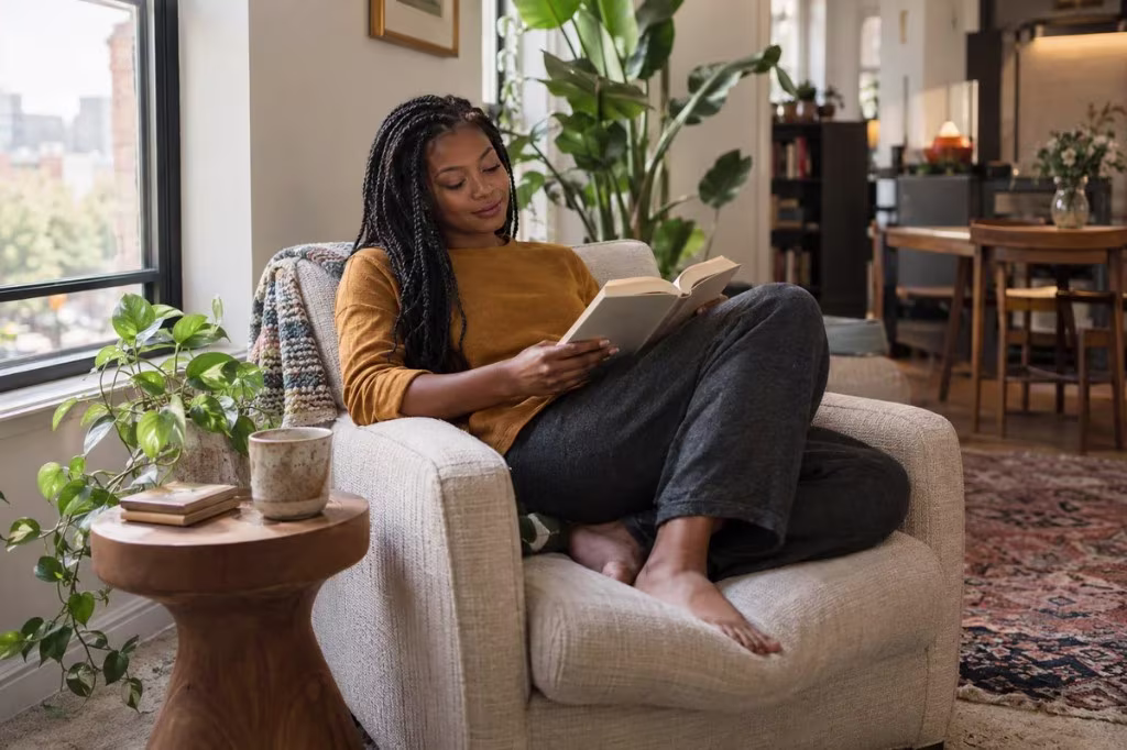 An introvert reads in a quiet living room chair, recharging with a book and time alone