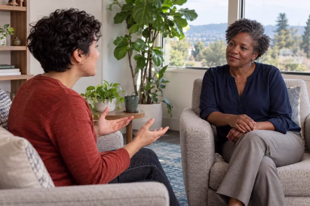 A client and therapist talk in a bright office with plants, affirming support for questions about demisexual identity